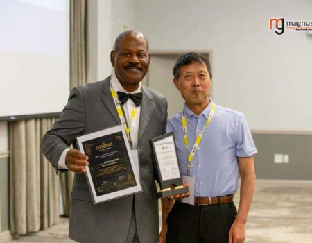 Two men proudly holding awards, smiling.